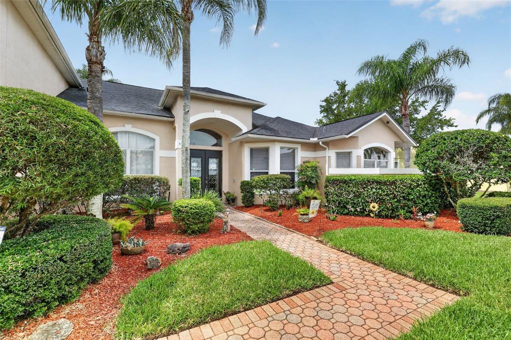 A single-story house with a brick walkway, palm trees, and manicured landscaping — 4552 LAKE CALABAY DRIVE, ORLANDO, FL