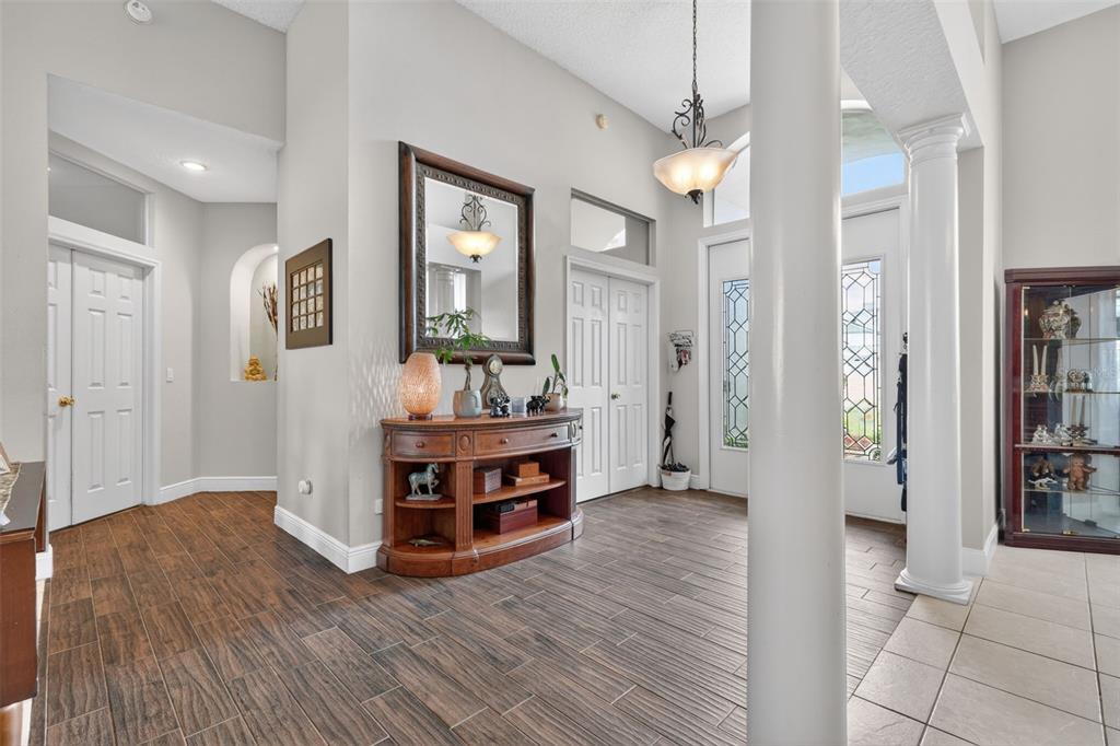An entryway features wood-look tile flooring, a central column, a console table, and a mirror — 4552 LAKE CALABAY DRIVE, ORLANDO, FL