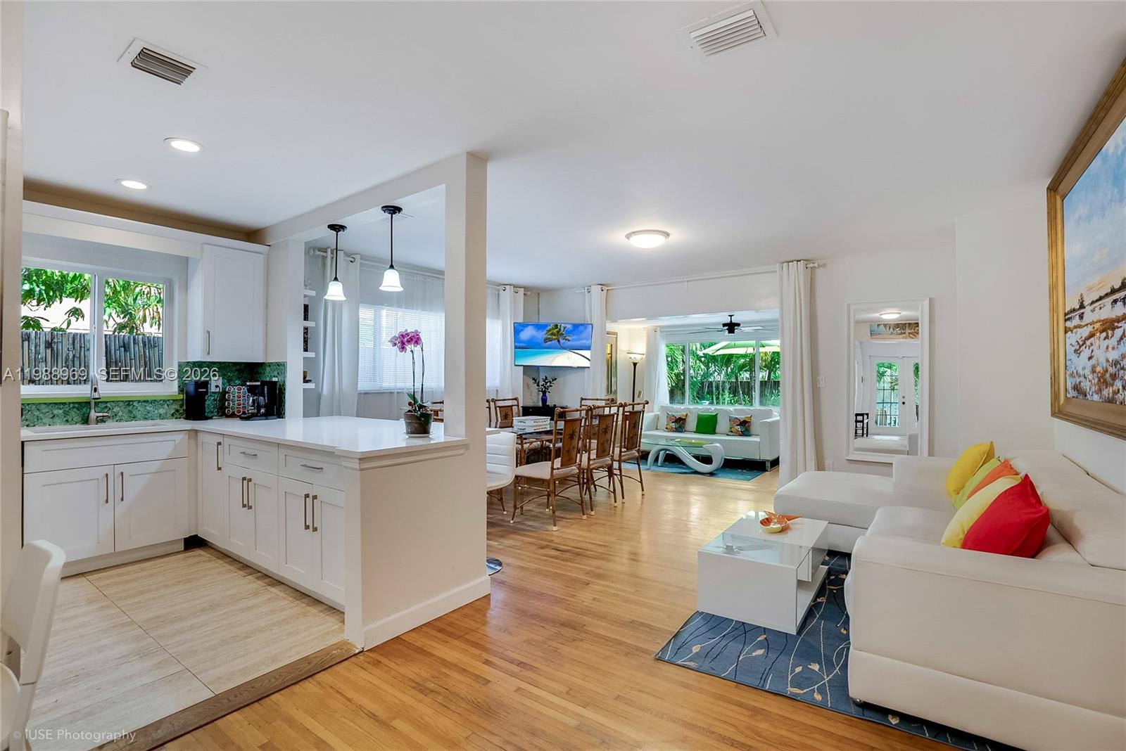 An open-concept living area features a white kitchen, dining space, and a bright living room — 113 SW 2nd St, Hallandale Beach FL 33009, HALLANDALE BEACH, FL