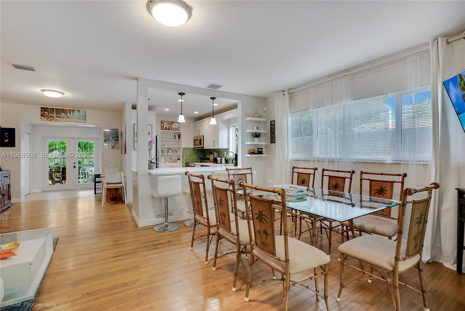 A dining area with a glass table and bamboo chairs sits adjacent to a kitchen — 113 SW 2nd St, Hallandale Beach FL 33009, HALLANDALE BEACH, FL