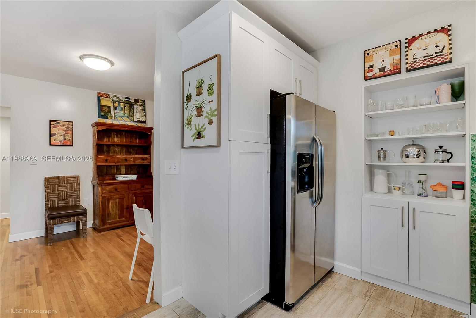A kitchen features white cabinetry, a stainless steel refrigerator, and an adjacent dining area — 113 SW 2nd St, Hallandale Beach FL 33009, HALLANDALE BEACH, FL