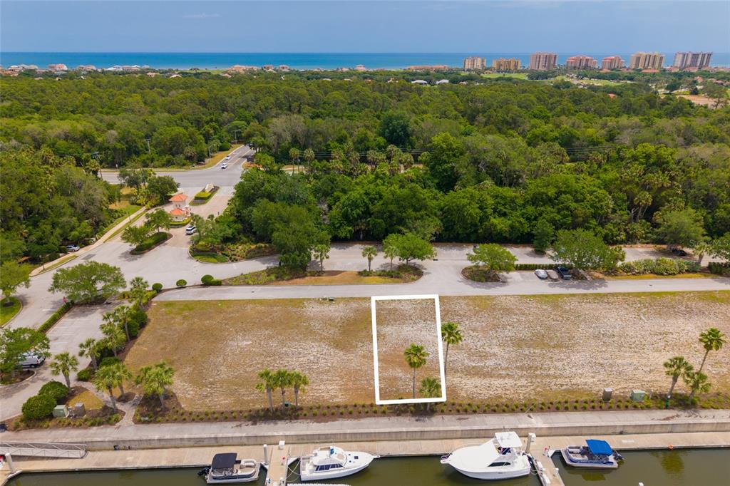 An aerial view shows a vacant rectangular lot situated along a marina with docked boats — 106 HARBOR VILLAGE POINT S, PALM COAST, FL