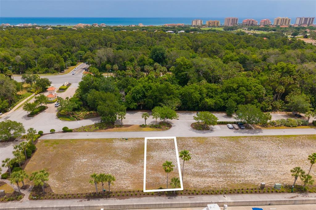 An aerial view shows a vacant rectangular lot outlined in white near a paved road — 106 HARBOR VILLAGE POINT S, PALM COAST, FL