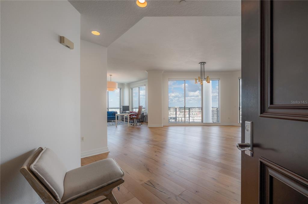 An open-concept living area features light wood flooring, floor-to-ceiling windows, and a modern chandelier — 449 S 12TH STREET UNIT 2701, TAMPA, FL
