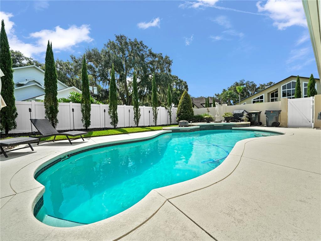 A backyard swimming pool with a concrete deck and a white privacy fence — 6556 CRESCENT LAKE DRIVE, LAKELAND, FL