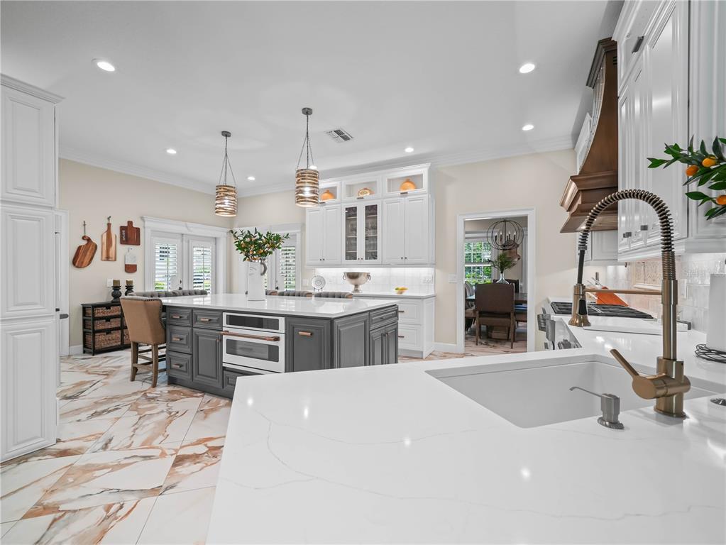 A modern kitchen features white cabinets, a gray island, and marble-patterned tile flooring — 6556 CRESCENT LAKE DRIVE, LAKELAND, FL