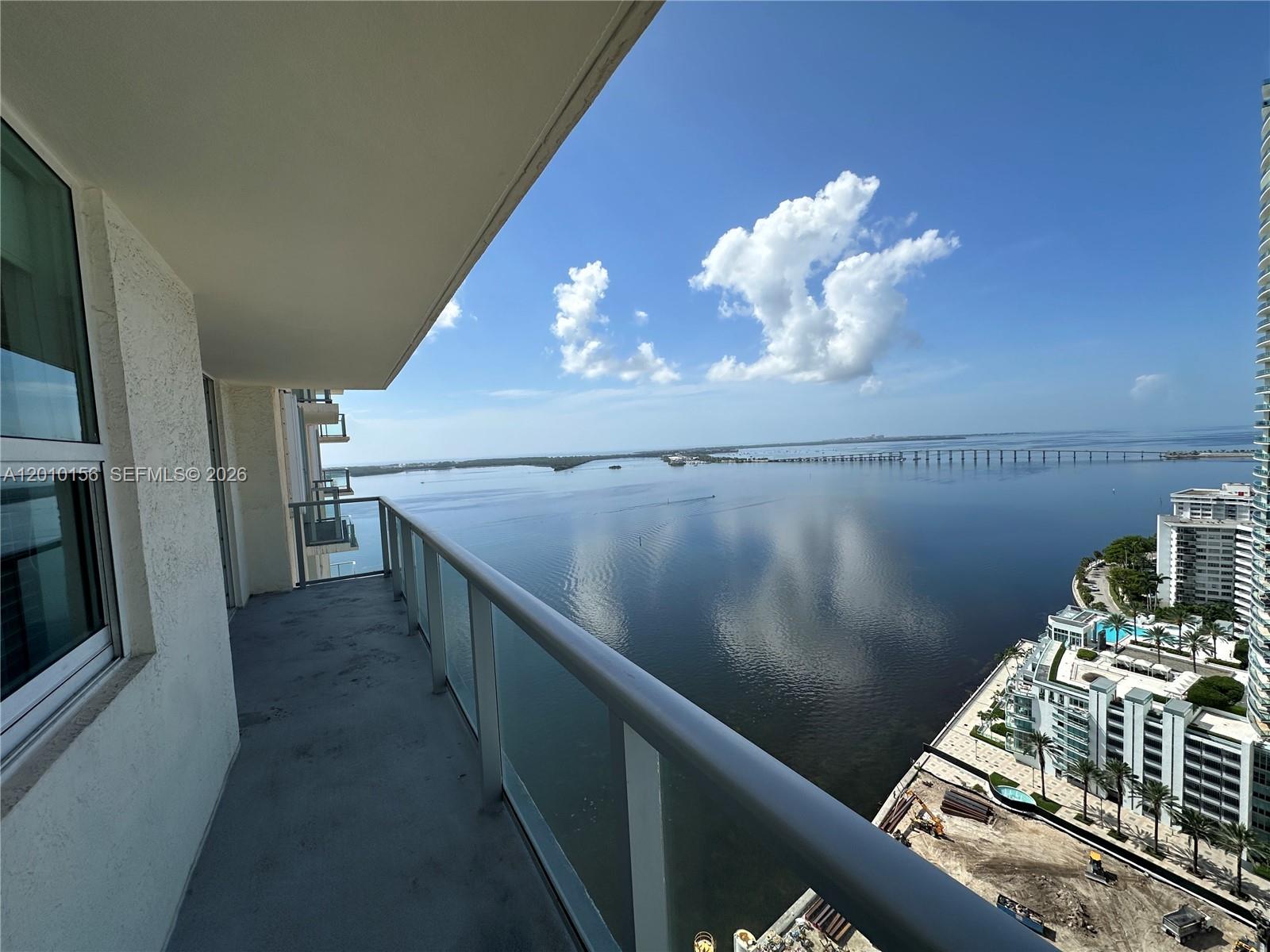 A high-rise balcony overlooks a large body of water with a bridge in the distance — 1155 Brickell Bay Dr # 3007, Miami FL 33131, MIAMI, FL