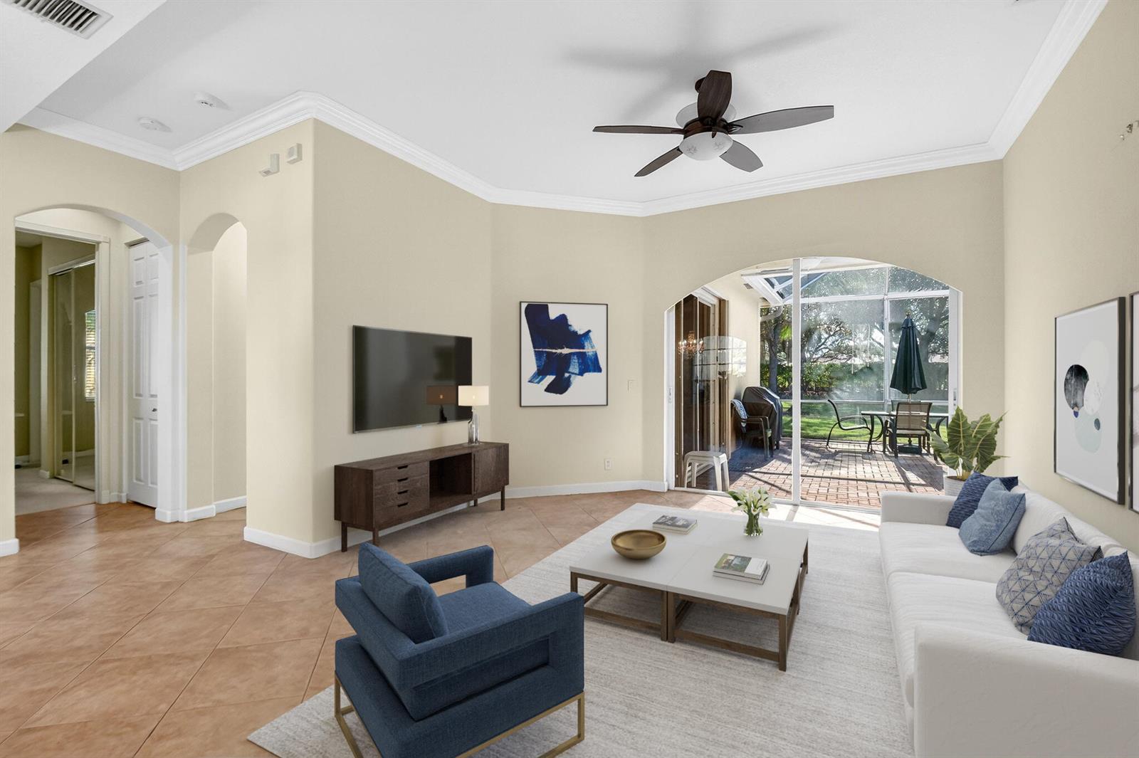 A living room features a white sofa, blue armchair, television, and sliding doors to a patio — 9566 Lantern Bay Circle, West Palm Beach FL 33411, WEST PALM BEACH, FL