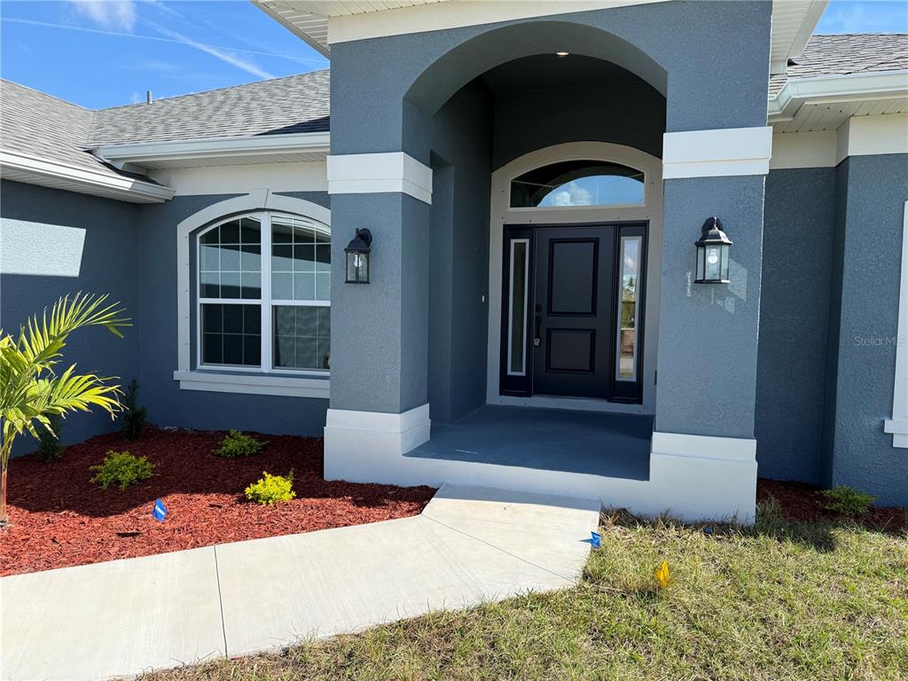 The exterior of a house features a dark blue facade, white trim, and a front entryway — 9227 NEWNAN CIRCLE, PORT CHARLOTTE, FL