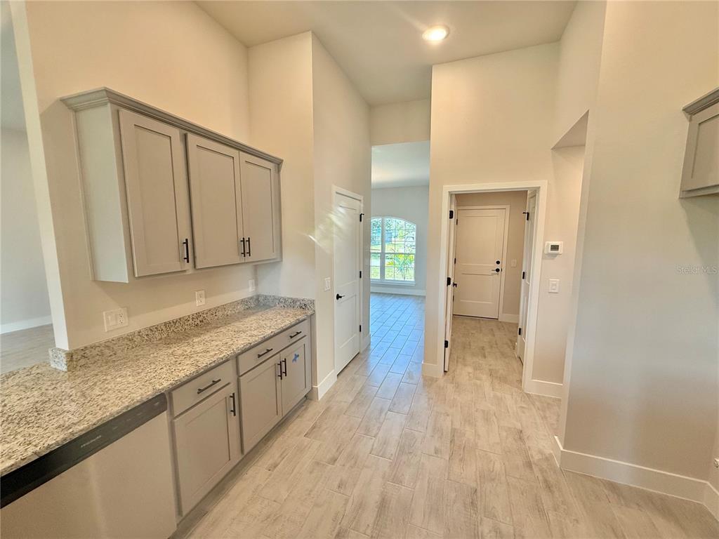 A kitchen area features gray cabinetry, granite countertops, and light wood-look tile flooring — 9227 NEWNAN CIRCLE, PORT CHARLOTTE, FL