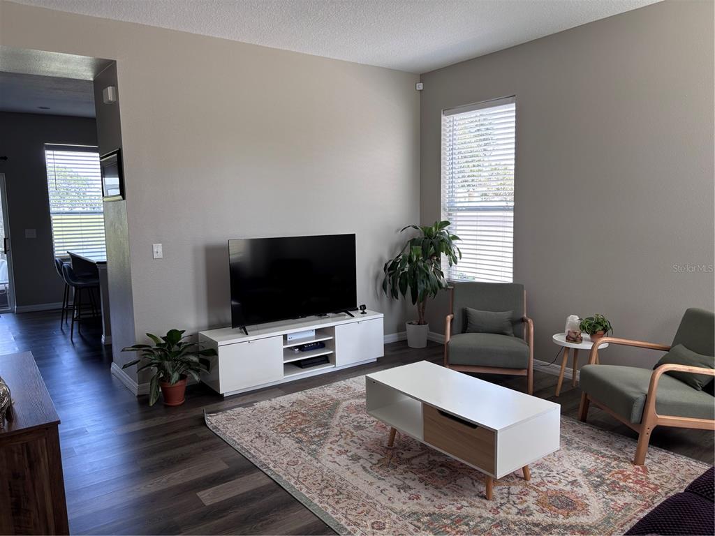 A living room features a television on a white console, two armchairs, and a rug — 2707 RANDAL WAY, KISSIMMEE, FL