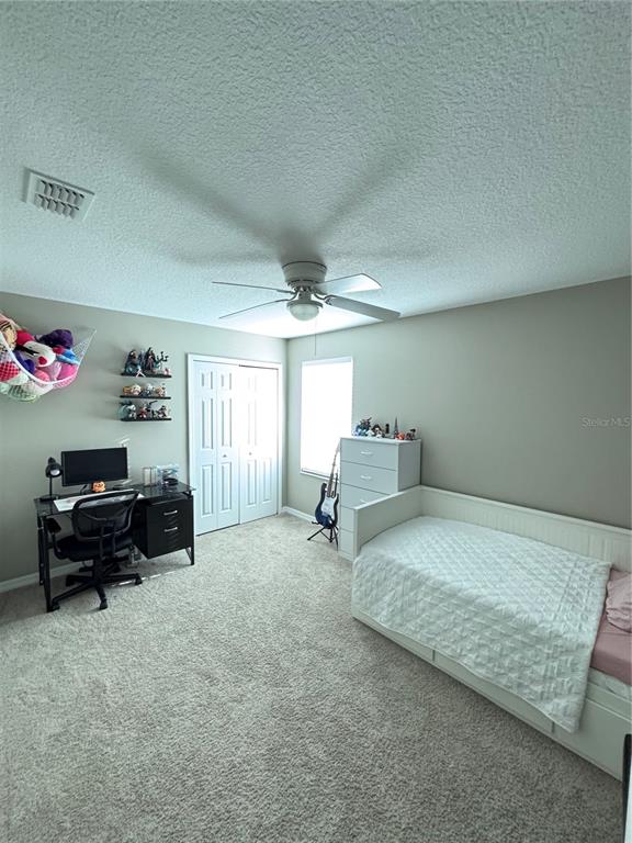 A bedroom features a desk, a daybed, a ceiling fan, and a closet with white doors — 2707 RANDAL WAY, KISSIMMEE, FL