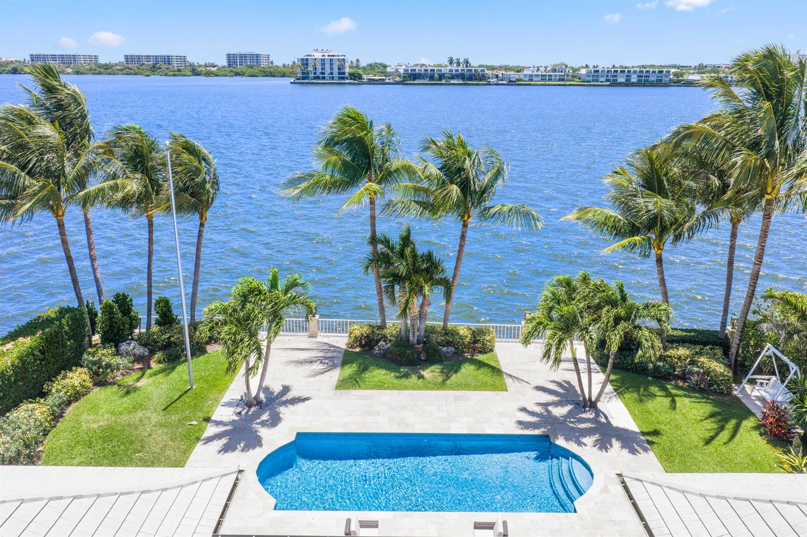 An aerial view of a swimming pool, patio, palm trees, and a waterfront bay — 2204 Notre Dame Drive, FL 33460, FL