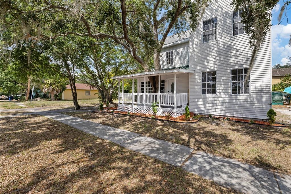 A two-story white house with a front porch built around a large tree — 7102 S FITZGERALD STREET, TAMPA, FL