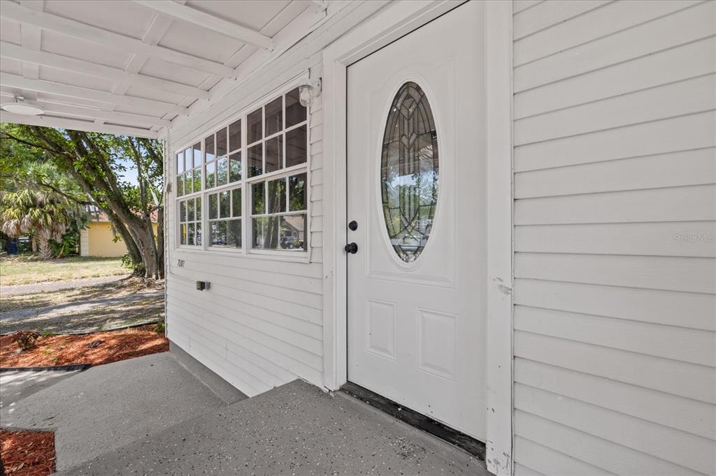 A white front door with an oval glass insert sits on a covered porch — 7102 S FITZGERALD STREET, TAMPA, FL