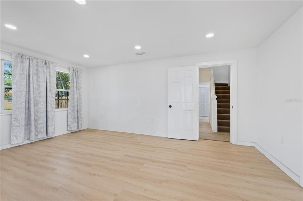 A room with light wood-look flooring, white walls, recessed lighting, and an open doorway — 7102 S FITZGERALD STREET, TAMPA, FL