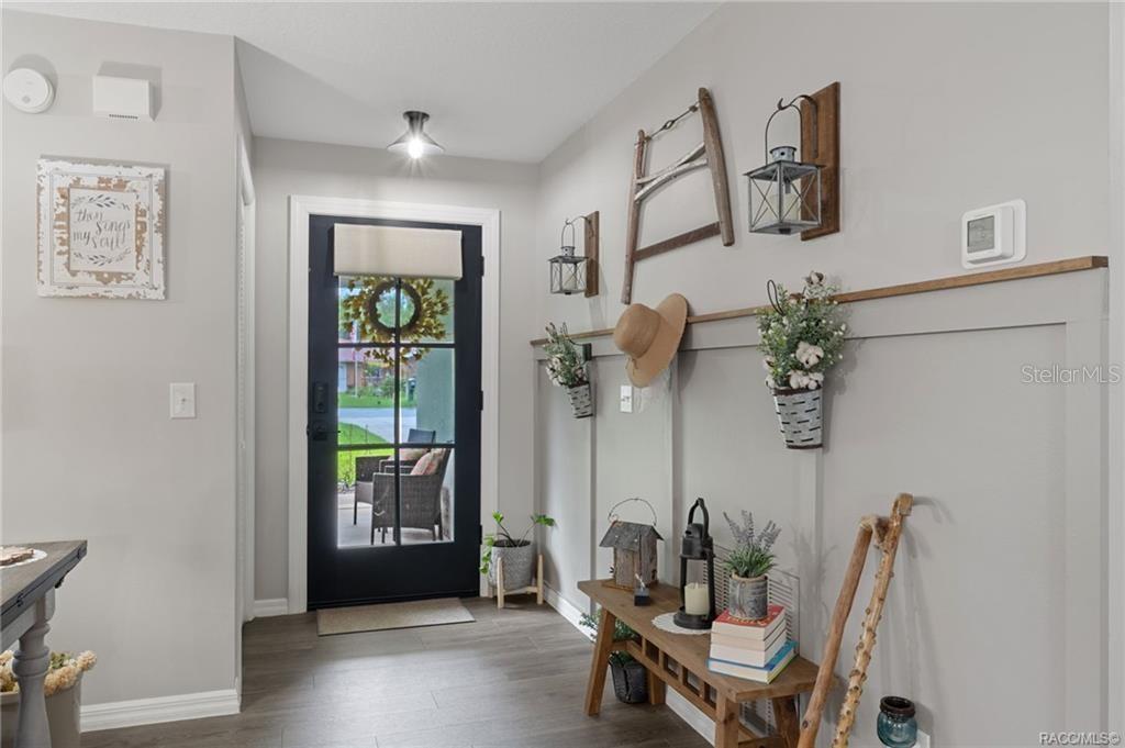 An entryway features a black front door, board and batten walls, and a wooden bench — 3218 S ROSE AVENUE, INVERNESS, FL