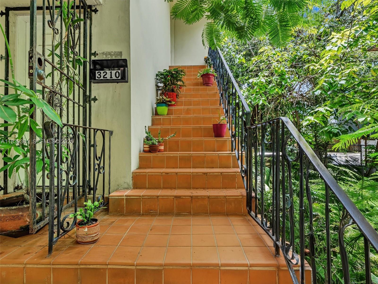 An outdoor staircase with orange tiles and black metal railings leads to a building entrance — 3210 E Elizabeth St, Miami FL 33133, MIAMI, FL
