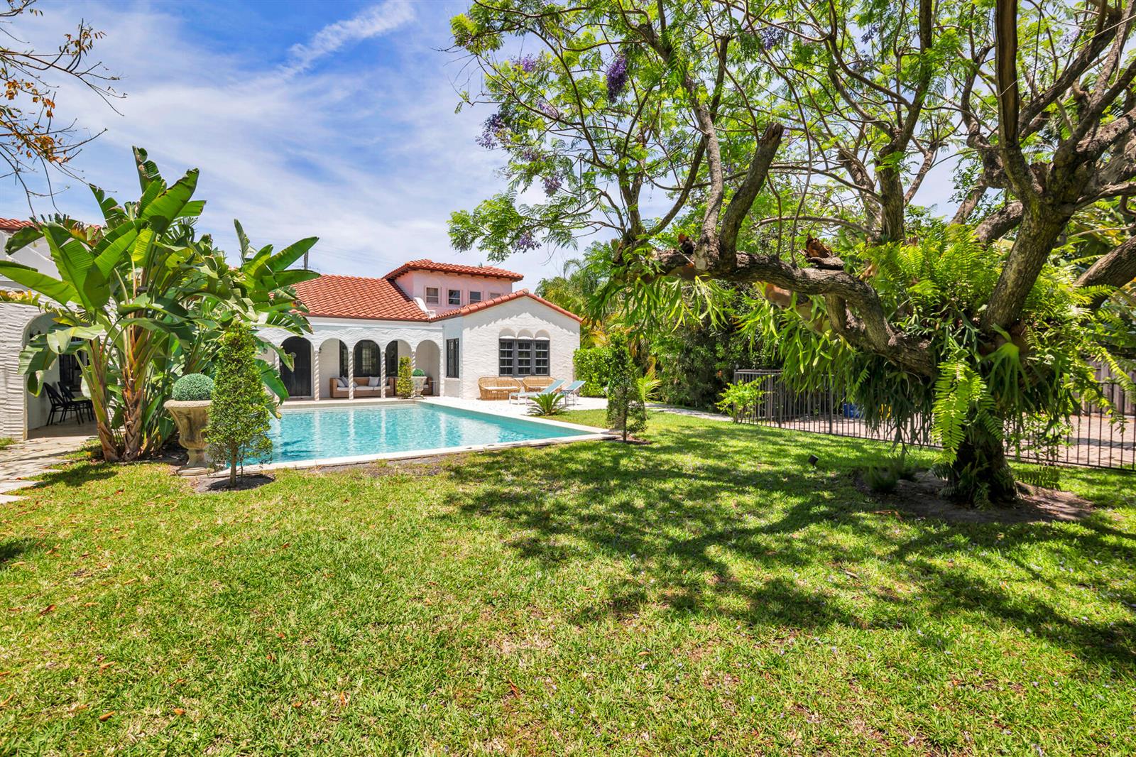 A backyard features a swimming pool, a white house with a red tile roof, and trees — 333 Murray Road, West Palm Beach FL 33405, WEST PALM BEACH, FL