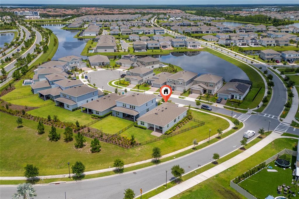 An aerial view shows a suburban neighborhood with houses, a pond, and landscaped green spaces — 13270 PANAMA BEACH COURT, ORLANDO, FL