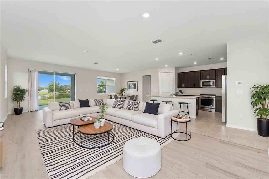 A bright open-concept living room features a large white sectional sofa and a modern kitchen — 13270 PANAMA BEACH COURT, ORLANDO, FL