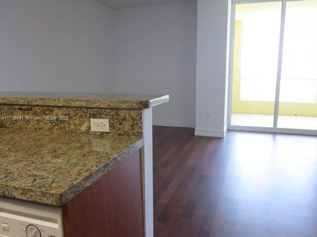 A kitchen counter with granite countertops overlooks a living area with dark wood-style flooring — 170 SE 14th St # 2306, Miami FL 33131, MIAMI, FL