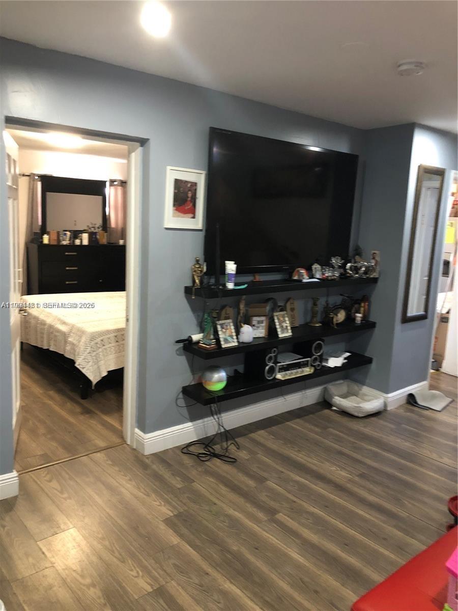 A living room features a wall-mounted television above three black floating shelves and wood-look flooring — 2231 SW 57th Ct, Miami FL 33155, MIAMI, FL