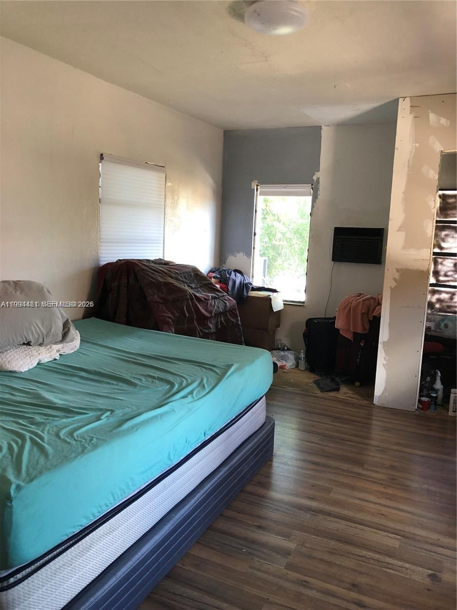 A bedroom features a bed with a teal sheet, wood-look flooring, and unfinished wall sections — 2231 SW 57th Ct, Miami FL 33155, MIAMI, FL