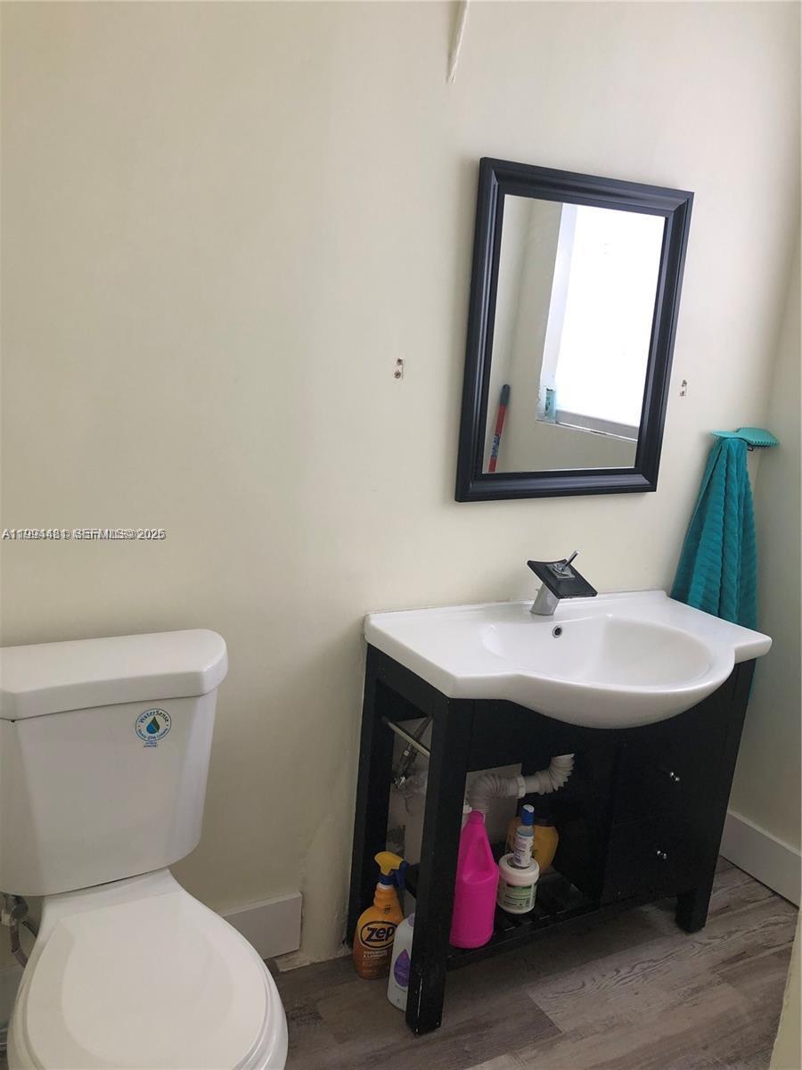 A bathroom features a white toilet, a black vanity with an open shelf, and a mirror — 2231 SW 57th Ct, Miami FL 33155, MIAMI, FL