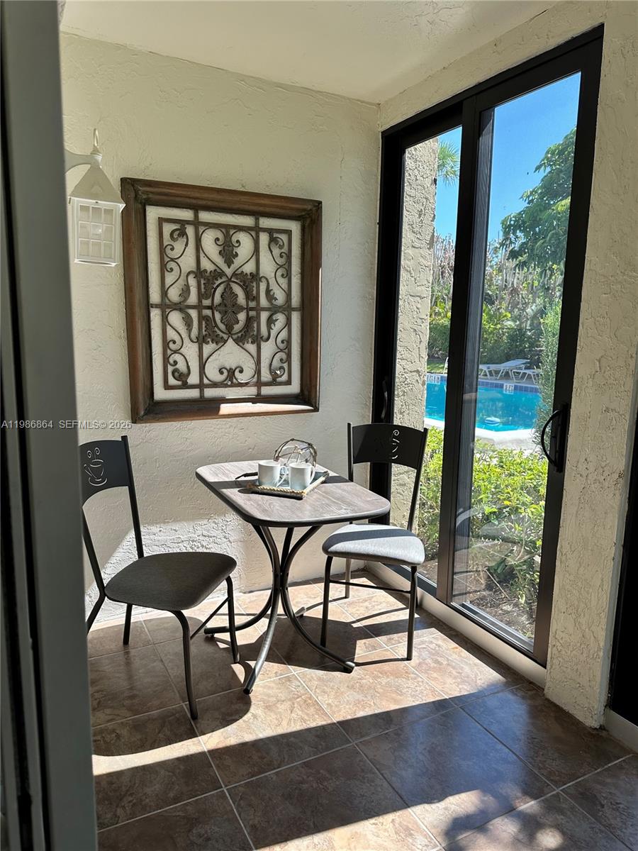 A small sunroom features a bistro table, two chairs, wall decor, and sliding glass doors — 4150 Highway A1A # 111, Vero Beach FL 32963, VERO BEACH, FL
