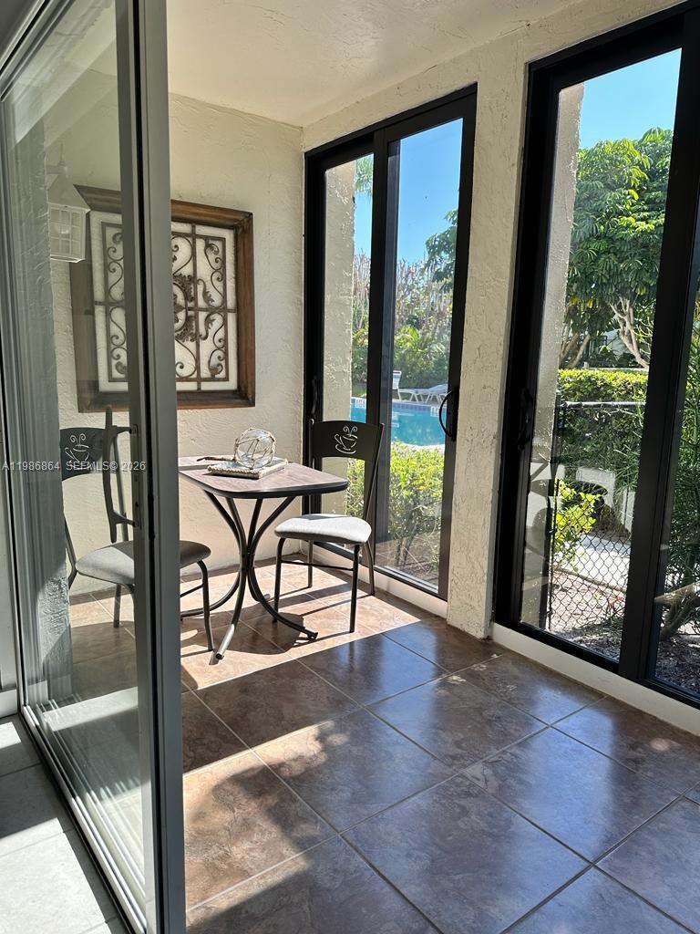 A sunroom with tiled floors, a small table with two chairs, and floor-to-ceiling windows — 4150 Highway A1A # 111, Vero Beach FL 32963, VERO BEACH, FL
