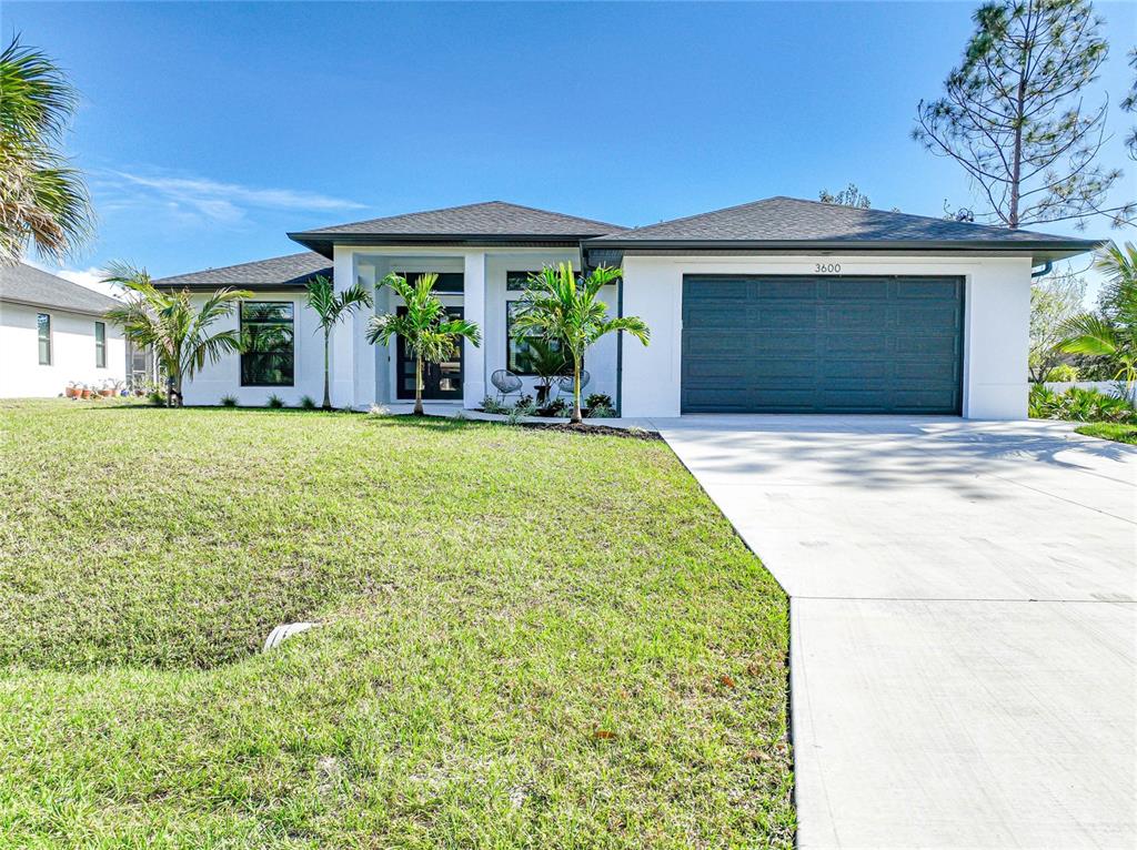 A single-story white house with a dark roof, a two-car garage, and palm trees — 3600 CINCINNATI STREET, NORTH PORT, FL