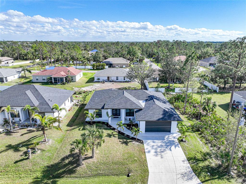 An aerial view of a modern single-story house with a dark shingled roof and driveway — 3600 CINCINNATI STREET, NORTH PORT, FL