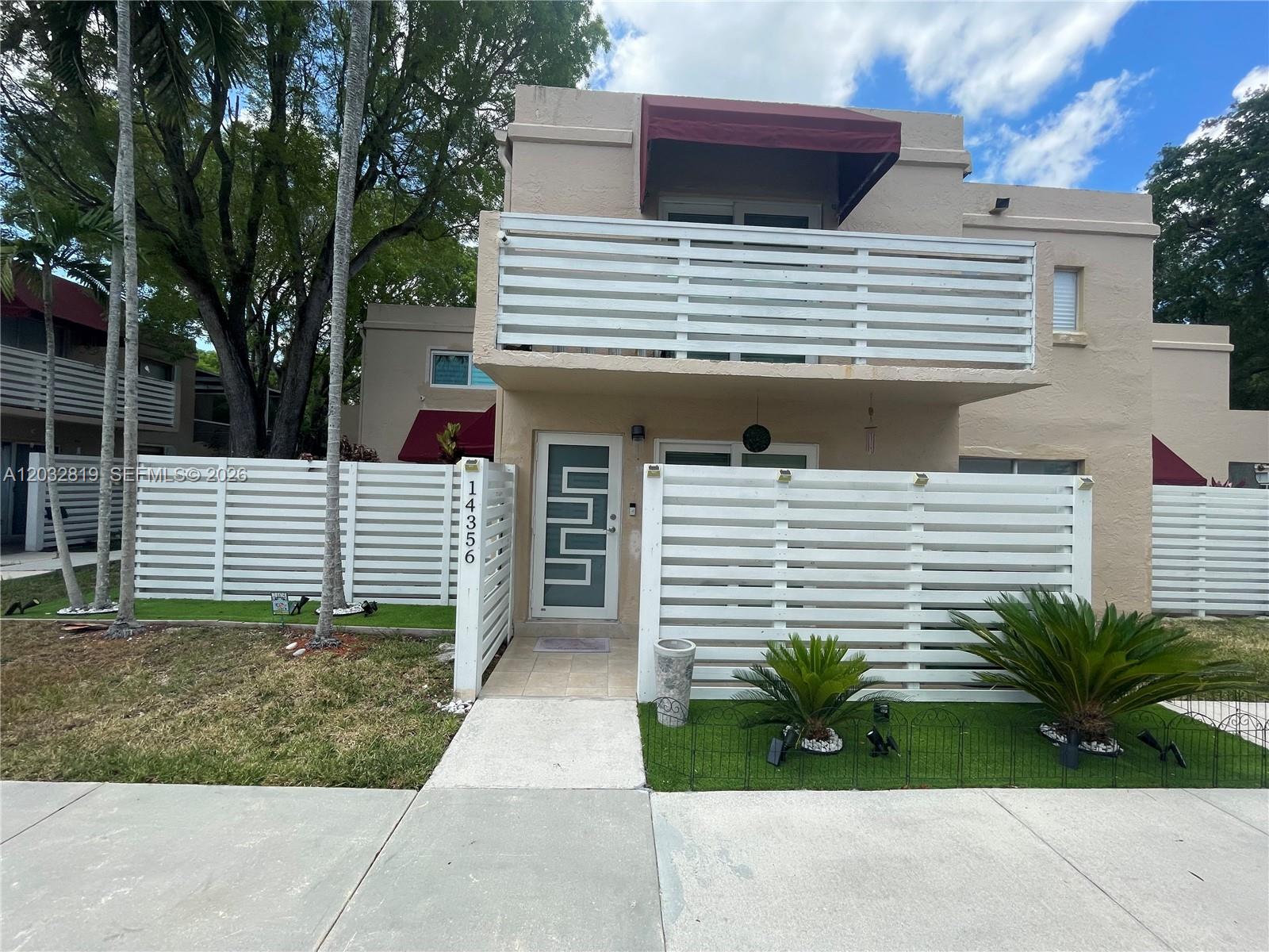 A two-story townhouse features a white horizontal fence, a balcony, and a modern front door — 14356 SW 96th Ter, Miami FL 33186, MIAMI, FL