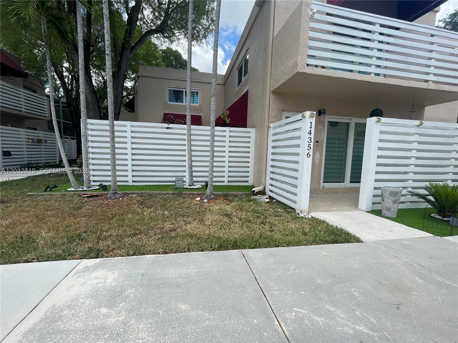 A two-story townhouse exterior features a white horizontal slat fence and a small front yard — 14356 SW 96th Ter, Miami FL 33186, MIAMI, FL