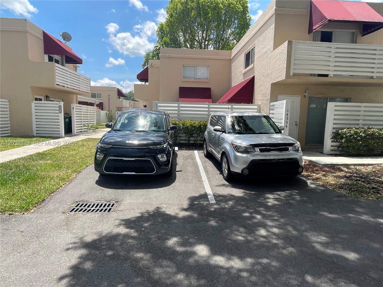 Two cars are parked in front of a multi-story residential building with red awnings — 14356 SW 96th Ter, Miami FL 33186, MIAMI, FL
