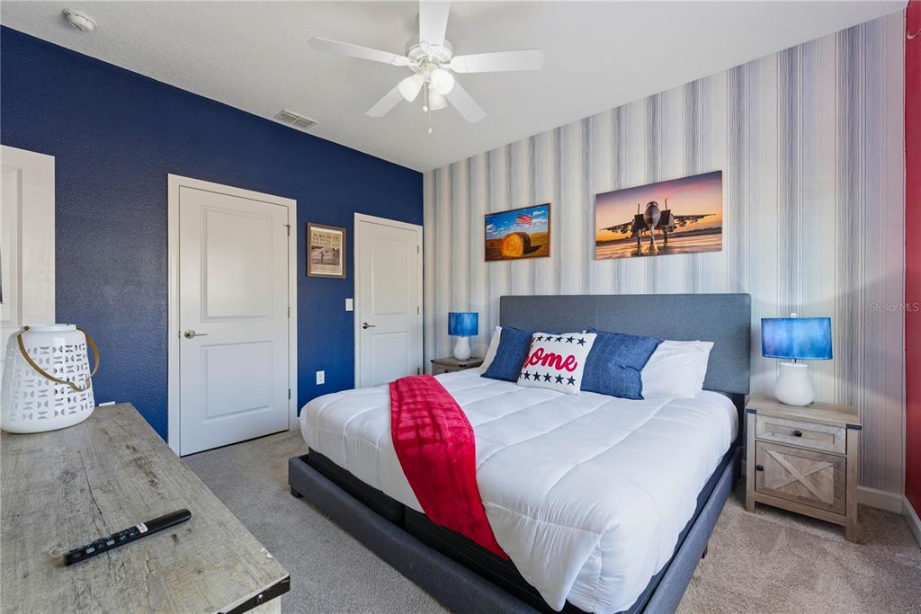 A bedroom features a king bed, blue accent wall, striped wallpaper, and two nightstands — 1112 CHALLENGE DRIVE, DAVENPORT, FL