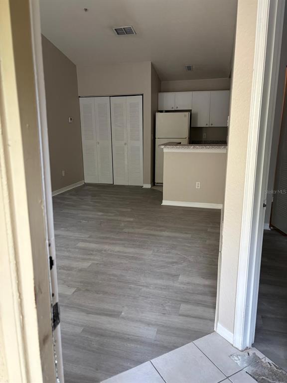 An interior view shows a living area with wood-look flooring, a closet, and a kitchen — 6336 RALEIGH STREET UNIT 1215, ORLANDO, FL
