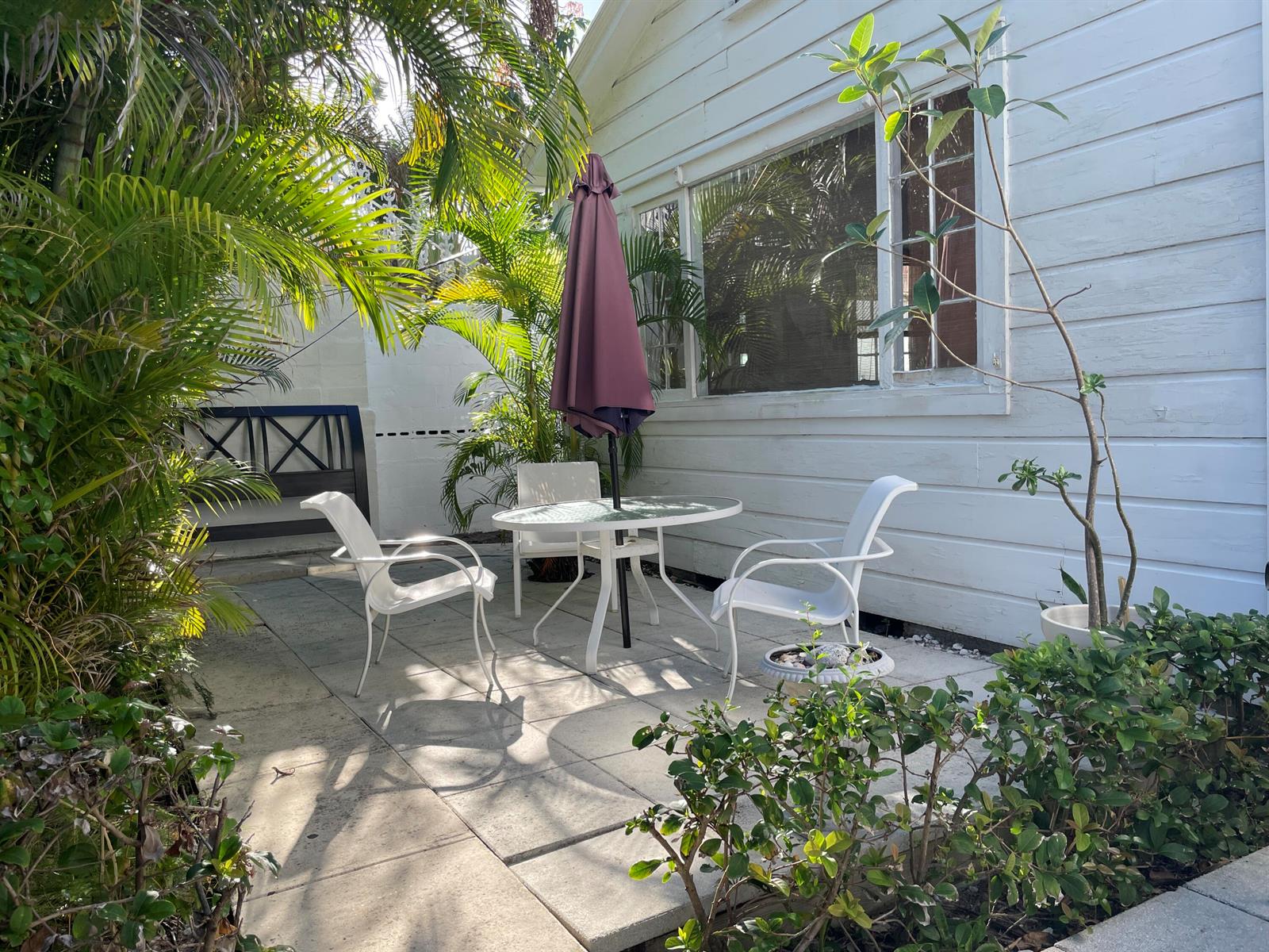 A patio with a glass-topped table, three white chairs, and a closed umbrella — 150 Australian Avenue, Palm Beach FL 33480, PALM BEACH, FL