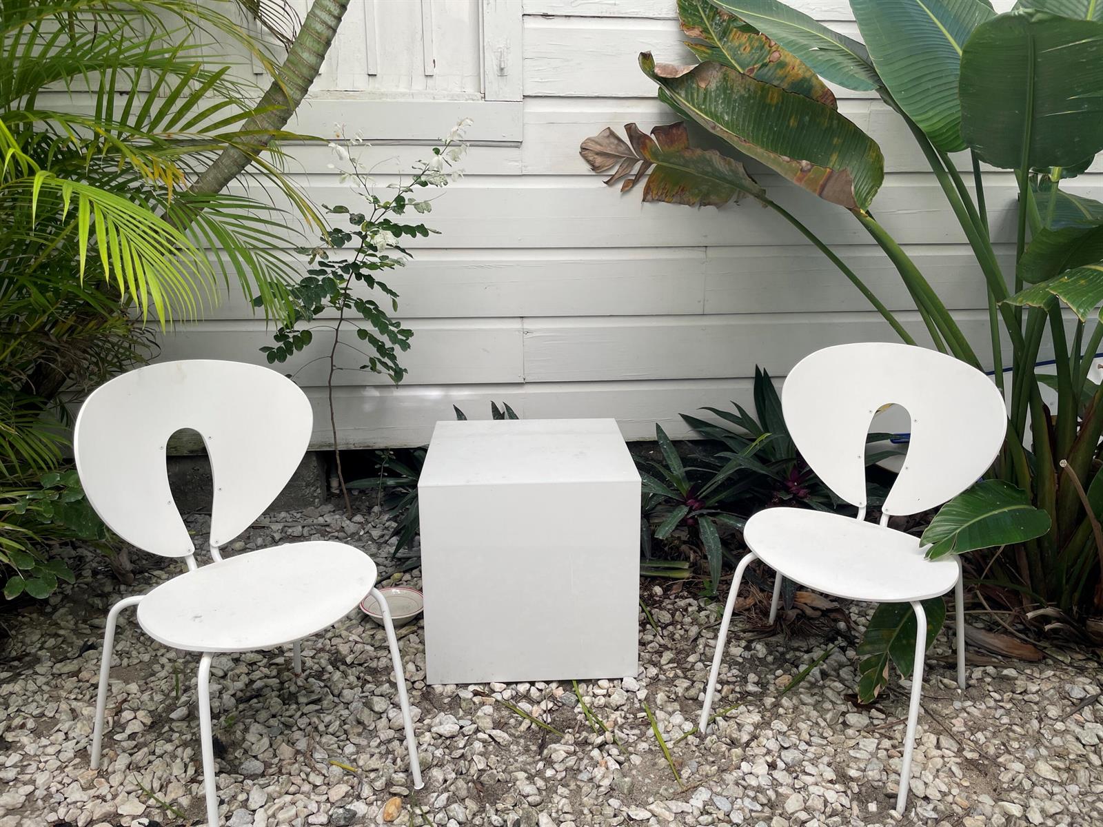 Two white chairs and a square table sit on a gravel patio by a wall — 150 Australian Avenue, Palm Beach FL 33480, PALM BEACH, FL
