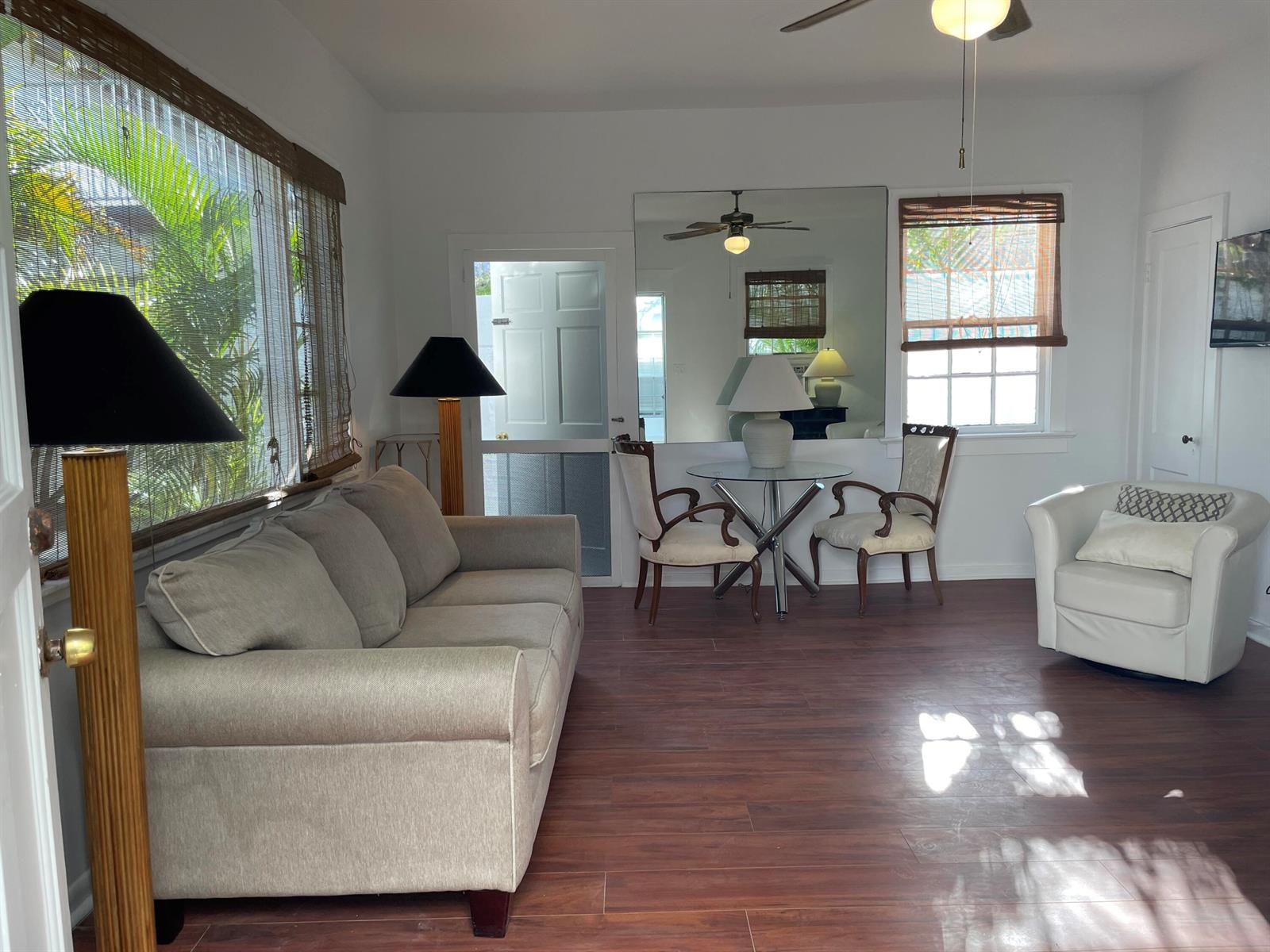 A living room with a sofa, dining set, mirror, and wood-look flooring — 150 Australian Avenue, Palm Beach FL 33480, PALM BEACH, FL