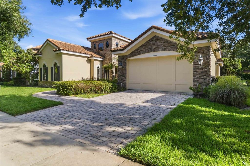 A single-story house with a tan stucco exterior, stone accents, and a tiled roof — 1298 BELLA VISTA CIRCLE, LONGWOOD, FL