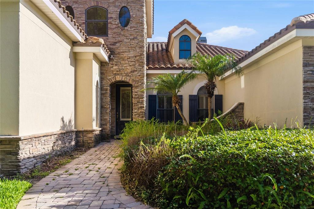 A single-story house with a stone facade, a two-car garage, and a paved driveway — 1298 BELLA VISTA CIRCLE, LONGWOOD, FL