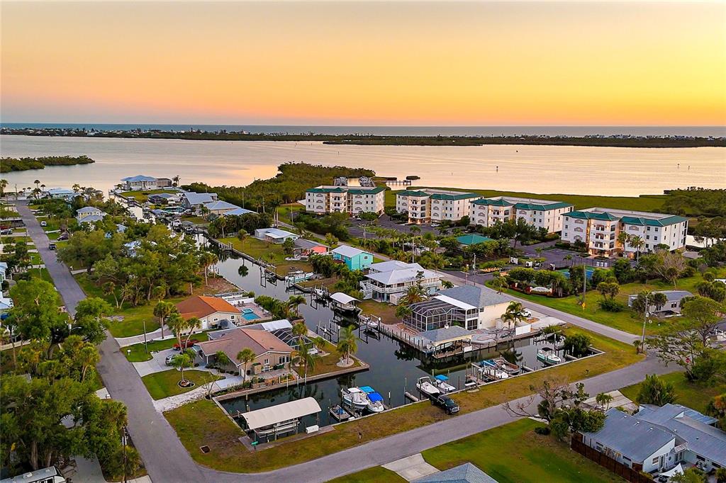 An aerial view of waterfront homes and apartment buildings along a canal at sunset — 9080 GRIGGS ROAD, ENGLEWOOD, FL