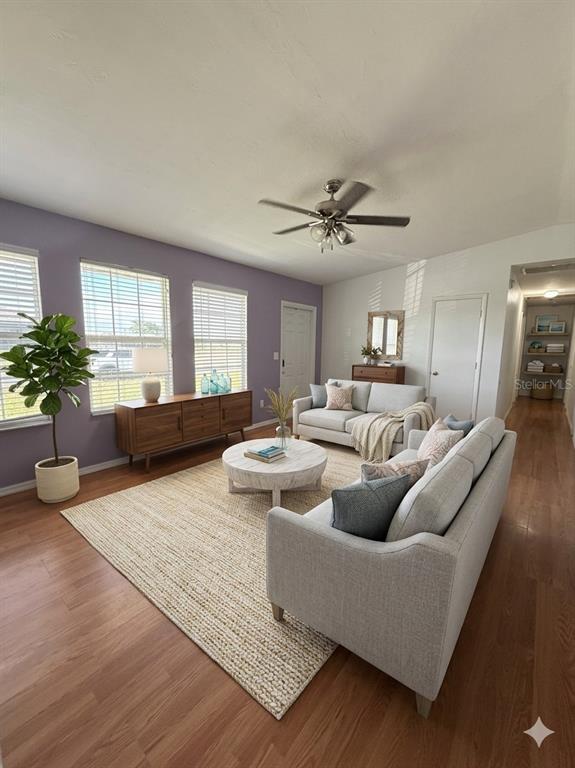 A living room features light wood flooring, a purple accent wall, and two gray sofas — 900 NE 18TH TERRACE, CAPE CORAL, FL