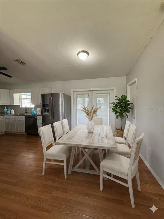 A dining area with a wooden table, six chairs, and a kitchen in the background — 900 NE 18TH TERRACE, CAPE CORAL, FL