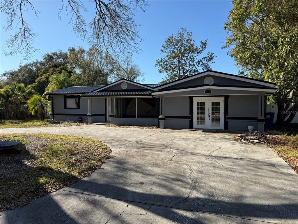 A gray single-story house with a metal roof and a large concrete driveway — 651 69TH AVENUE S, ST PETERSBURG, FL