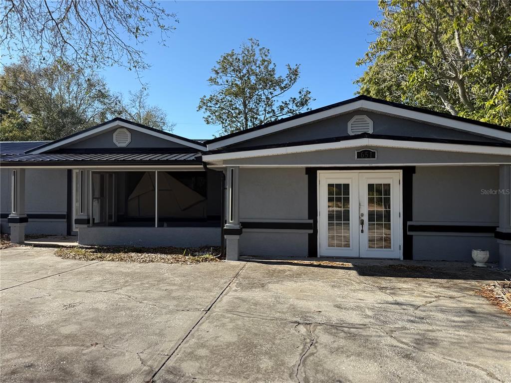 A gray house exterior features a concrete driveway, double front doors, and a screened porch — 651 69TH AVENUE S, ST PETERSBURG, FL