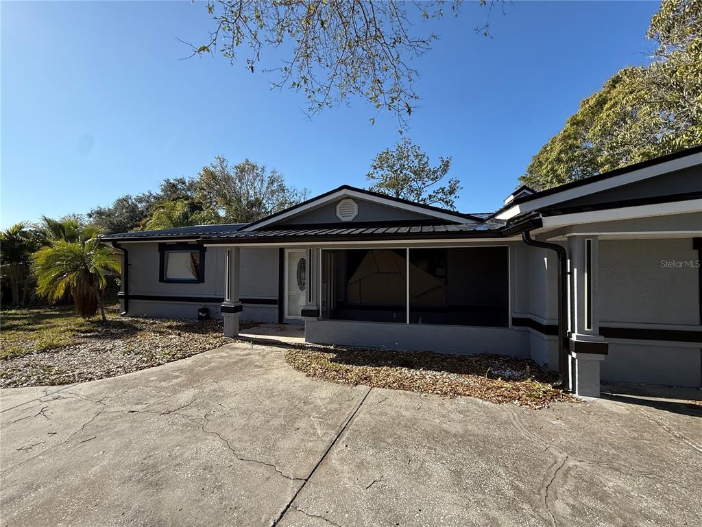 A gray single-story house with a metal roof, a screened porch, and a concrete driveway — 651 69TH AVENUE S, ST PETERSBURG, FL
