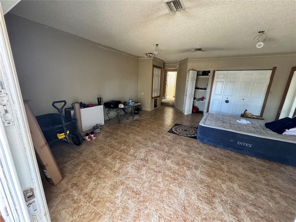 A room with beige walls, tiled floors, an inflatable mattress, and open closet doors — 651 69TH AVENUE S, ST PETERSBURG, FL